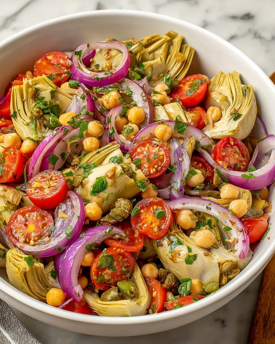 Large white bowl filled with a vibrant Mediterranean artichoke salad featuring whole marinated artichoke hearts, halved cherry tomatoes, thinly sliced red onions, chickpeas, capers, and fresh chopped herbs, all lightly dressed with olive oil and seasoning, perfectly tossed and presented in a full serving bowl, photographed from a 3/4 angle on a white marble countertop with natural lighting, professional food styling photo taken with an iphone --ar 4:5 --v 7