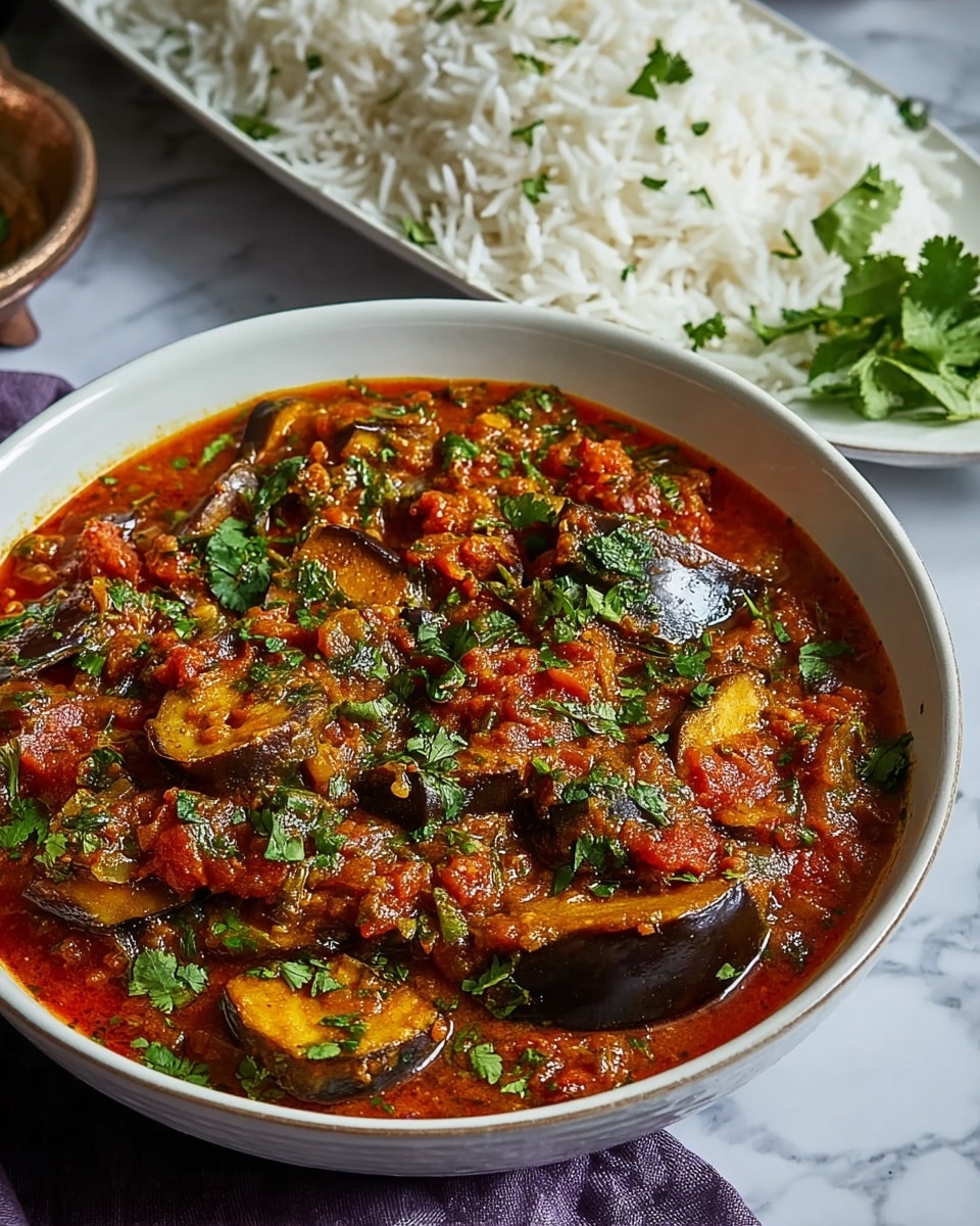 Large white ceramic bowl filled with a vibrant, hearty eggplant curry simmered in rich tomato and spice sauce, garnished generously with fresh chopped cilantro, accompanied by a white rectangular serving platter piled high with fluffy basmati rice, arranged on a white marble countertop with natural lighting, professional food magazine style hero shot captured from a 3/4 angle, entire dish fully visible in frame, photo taken with an iphone --ar 4:5 --v 7