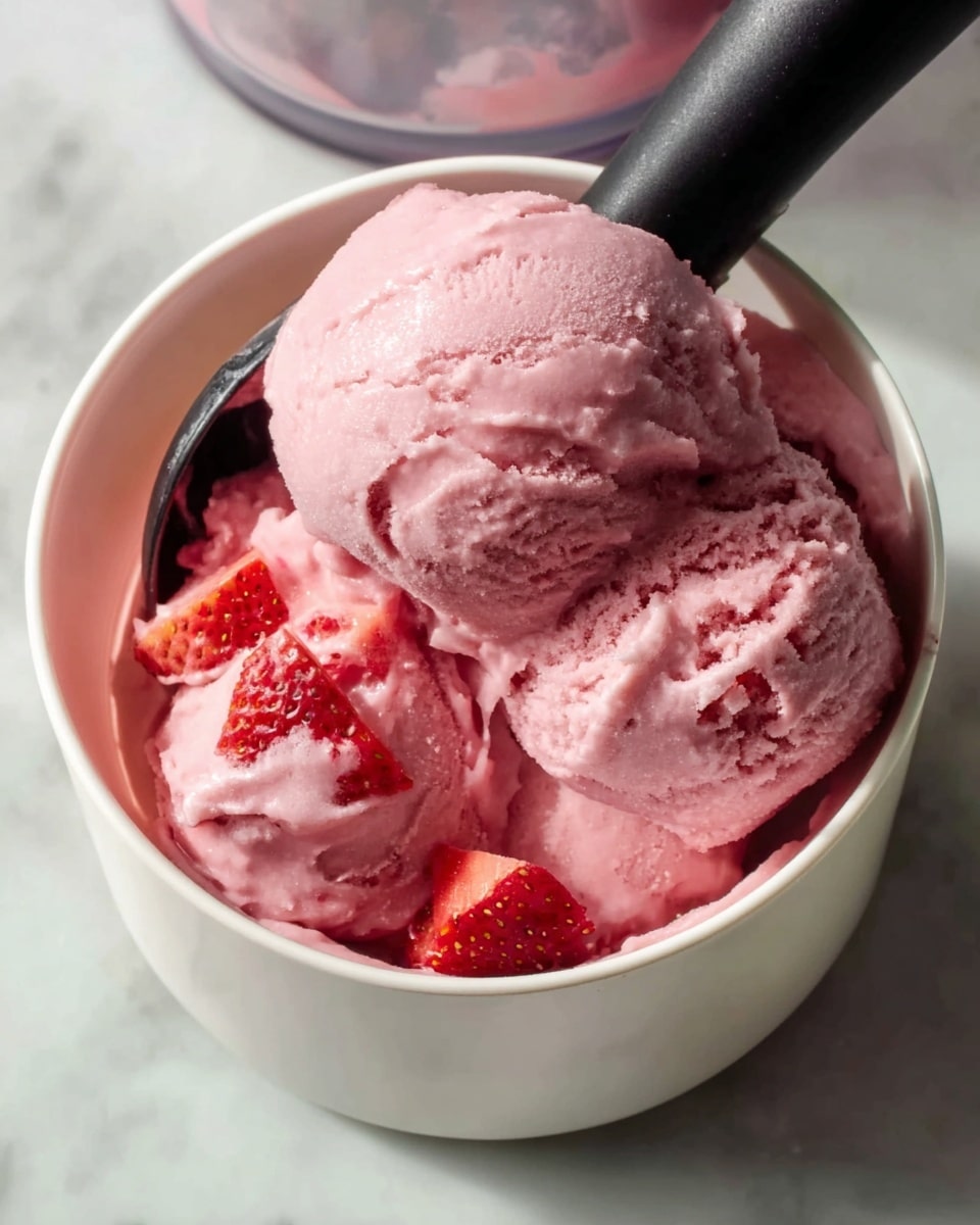 Large white bowl filled with smooth and creamy pink strawberry ice cream, showing the entire batch with a soft, velvety texture and rich strawberry color, garnished with fresh strawberry pieces, photographed from a 3/4 angle on a white marble countertop with natural lighting, professional food styling photo taken with an iphone --ar 4:5 --v 7